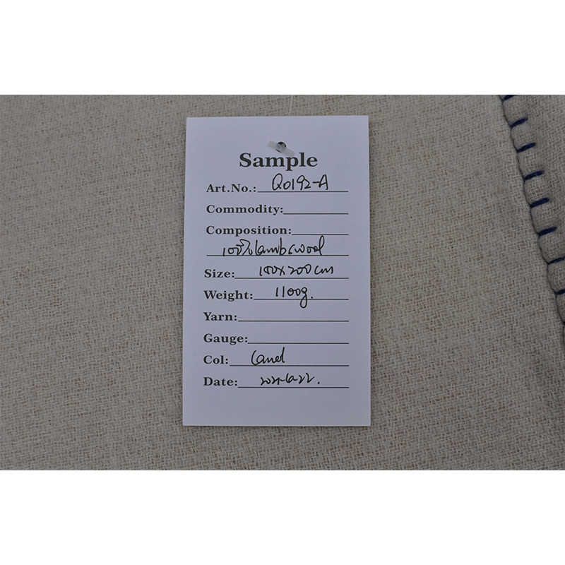 Q0192-A sample label confirming 100% lambswool composition, 140 × 200 cm size and approximately 1100 g weight.