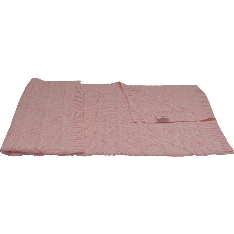 Pink organic cotton knit baby blanket with cable pattern hanging display