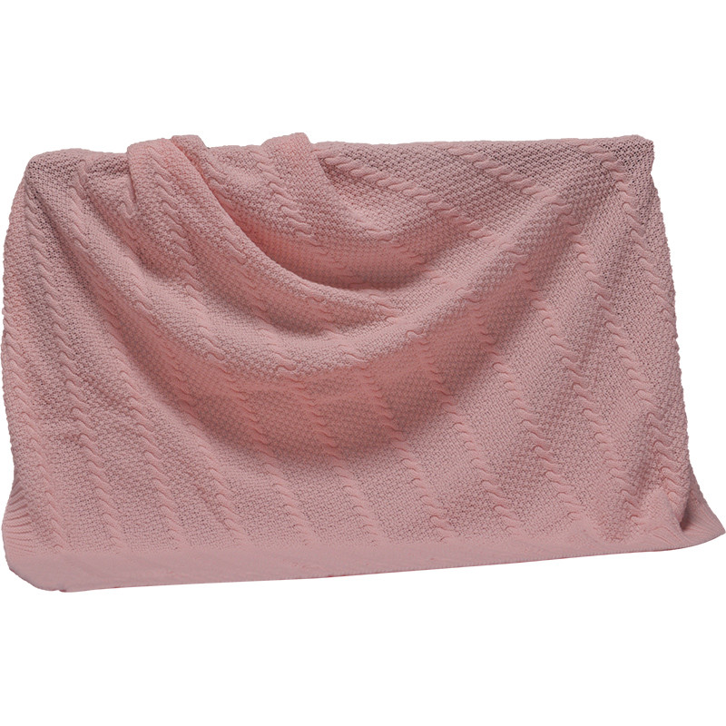Pink organic cotton nursery blanket styled on furniture and hanging