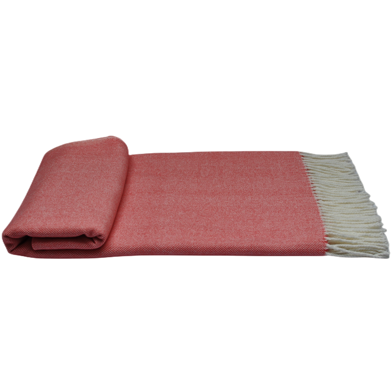 Folded coral herringbone throw blanket showing textured surface and side fringe detail.