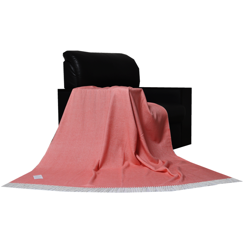 Coral herringbone throw blanket draped over a black armchair.