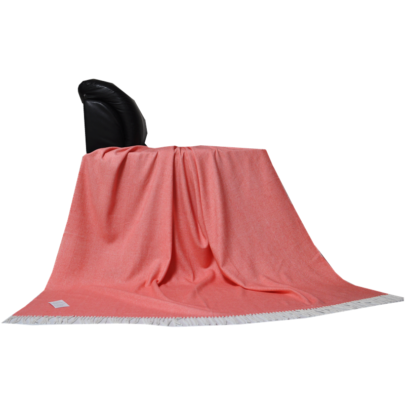 Side profile view of a coral herringbone throw blanket draped over a chair.