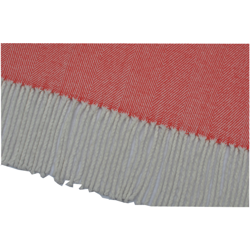 Close-up detail of white knotted fringe on a coral herringbone blanket.