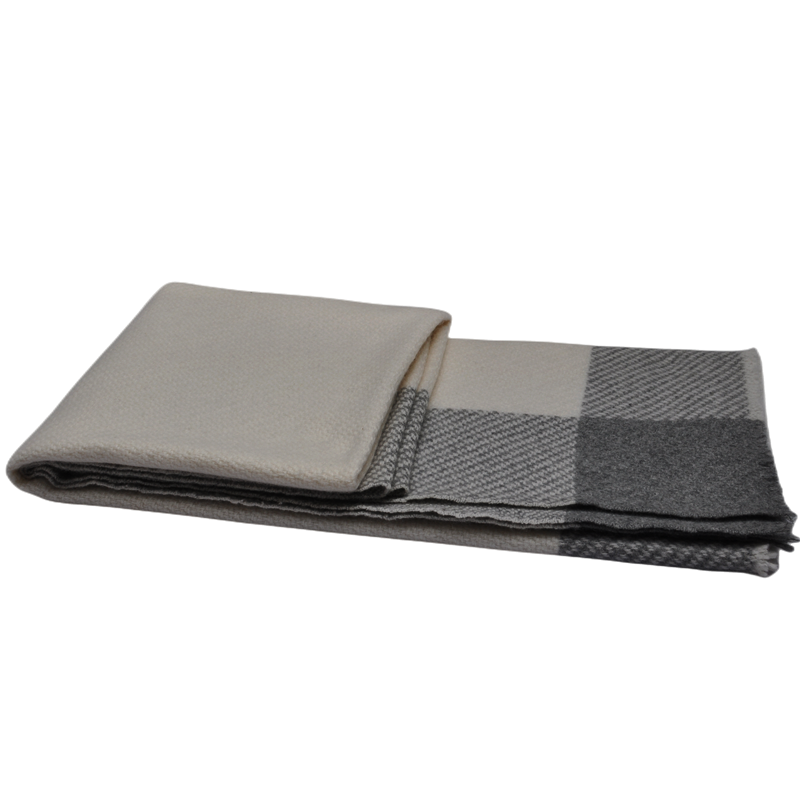 A rectangular folded cashmere blanket in a cream and grey patchwork design, showing the thickness of the layers.