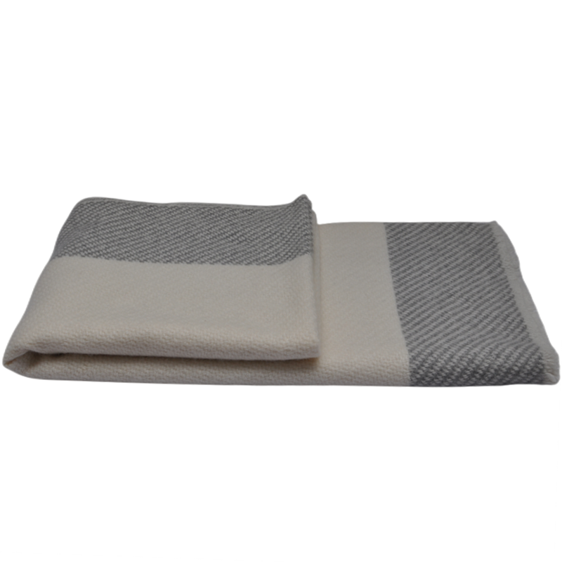 A neatly folded pashmina shawl featuring a solid cream top layer and a grey-and-white twill patterned side.