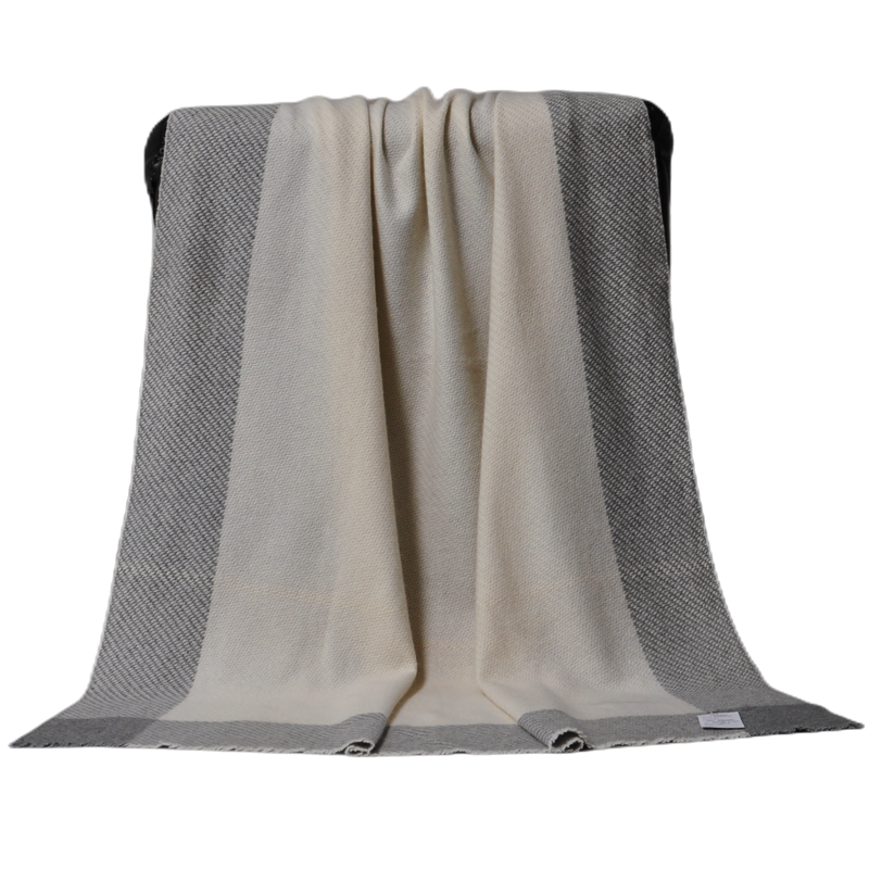 A detailed view of the blanket hanging over a chair back, showing the natural drape and soft texture of the fabric.
