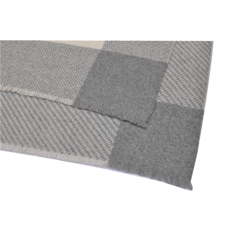A close-up of the blankets edge, featuring a fine eyelash fringe finish and color-block stitching.