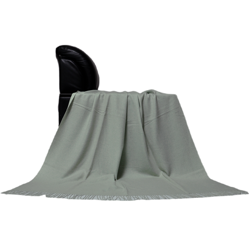 Front view of the E1108 green melange cashmere wool blanket displayed over a chair.