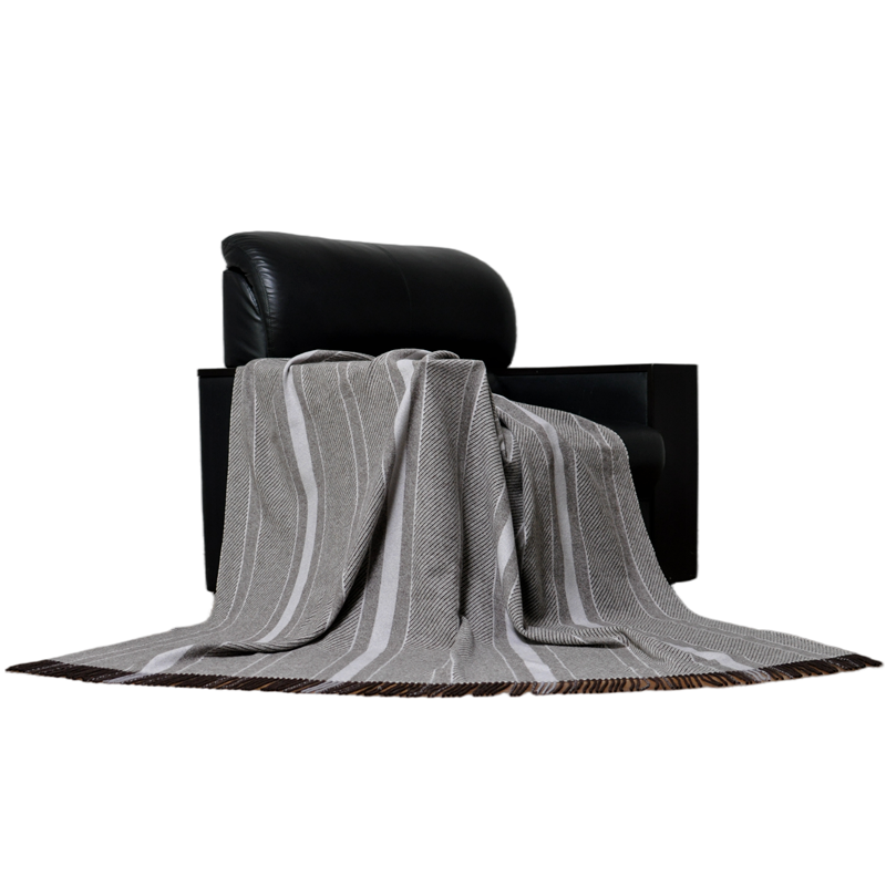 Striped natural fiber blanket draped over a chair, suitable for hotel and home decor wholesale.