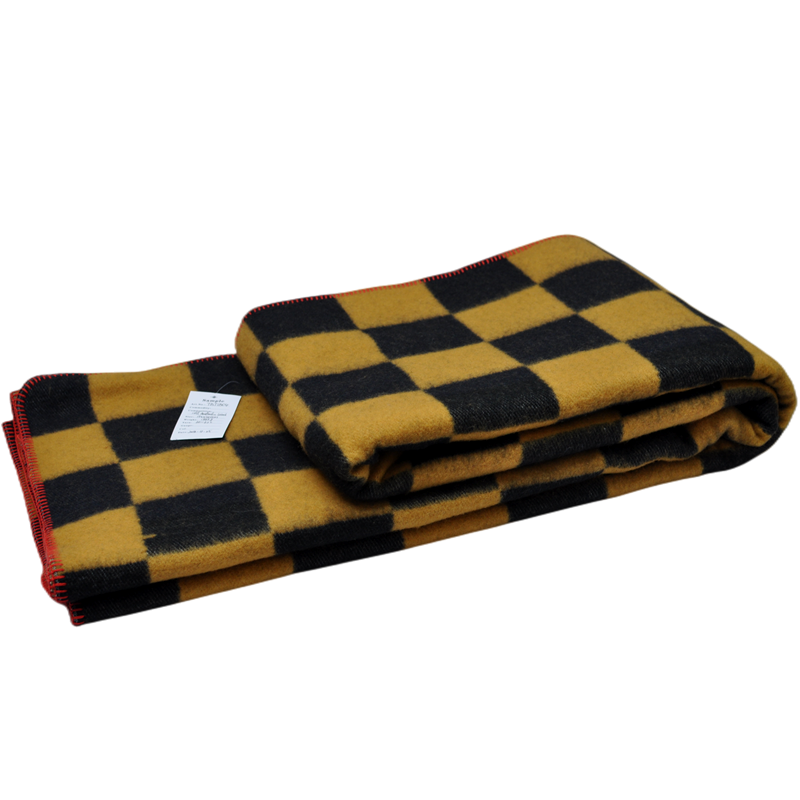 Layered TBT1804 wool checkerboard blanket showing its substantial construction, product label and red stitched perimeter