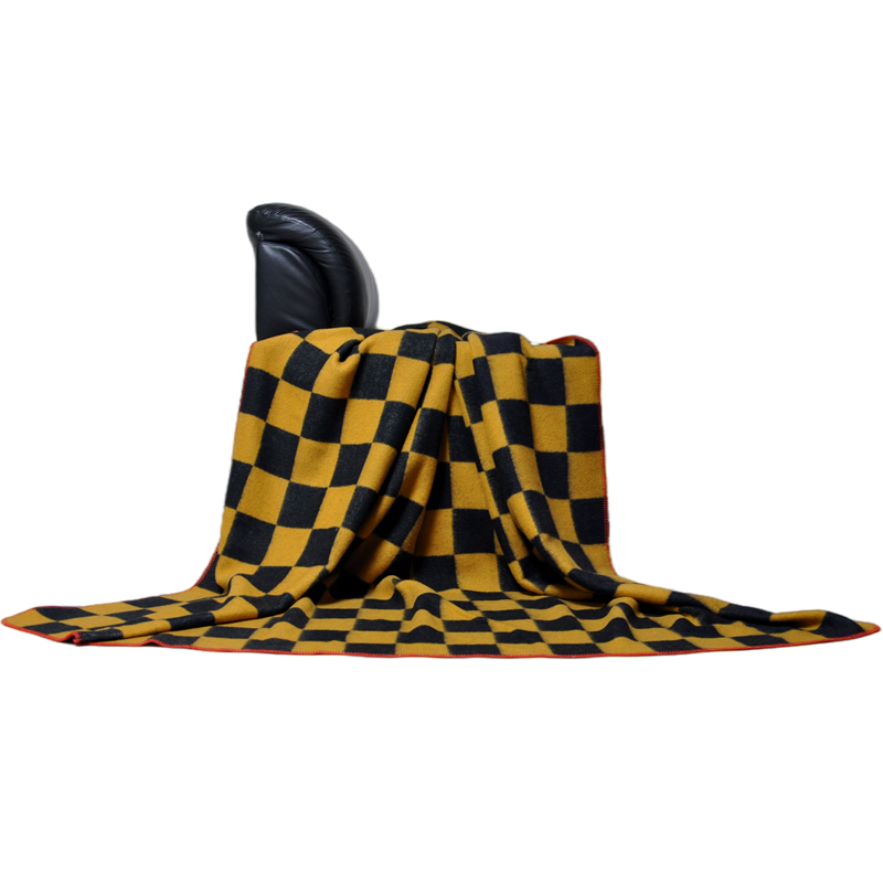 Front view of the TBT1804 Australian wool checkerboard blanket draped across a chair with the red edge visible