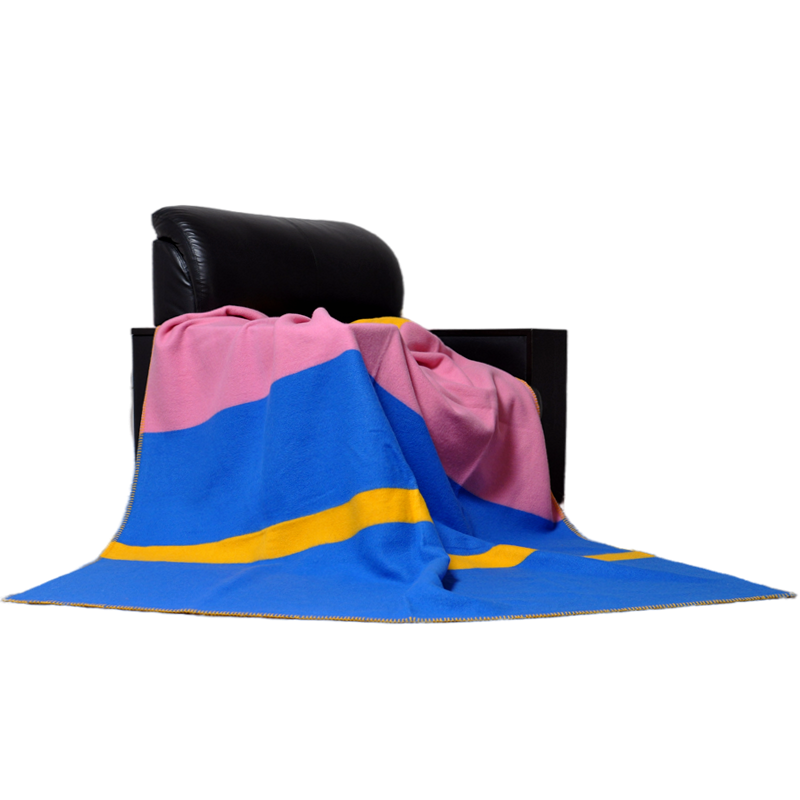 Color block pink blue yellow pure wool throw blanket draped over black leather armchair home interior decor lifestyle shot