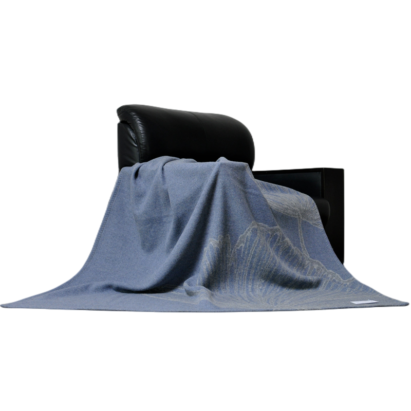 Oriental dusty blue ginkgo wool throw draped on black leather armchair home decor shot
