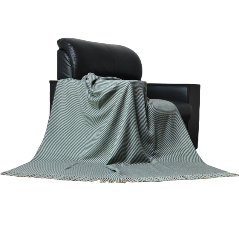 TDL1901 wool acrylic throw draped across a black armchair with grey diagonal stripes and fringe spread in front