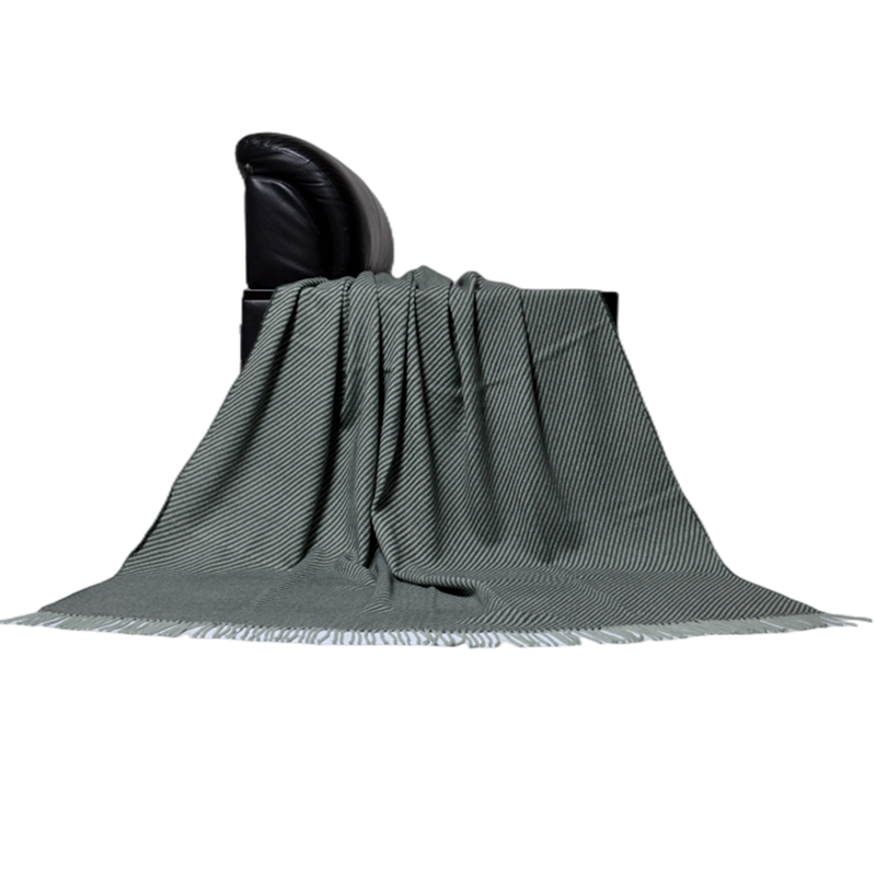 Side view of TDL1901 striped wool blend blanket draped over a black armchair with its fringed edge visible
