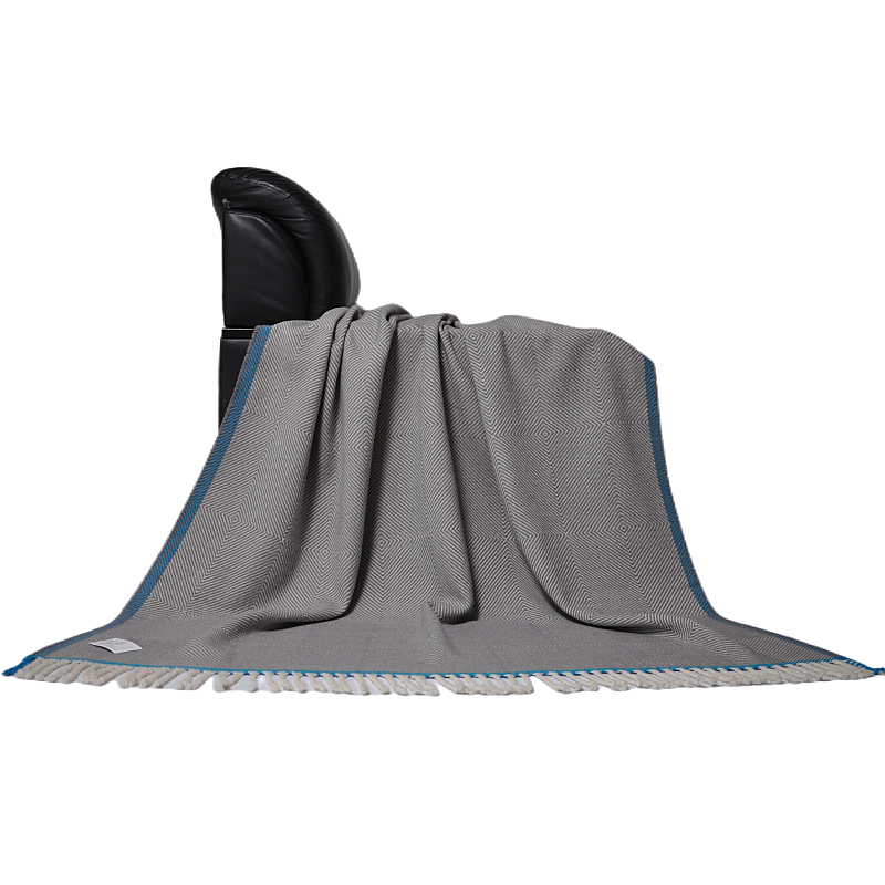 Wool herringbone throw blanket draped on a black leather chair