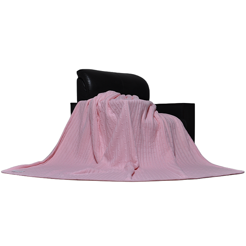 Classic pink cable knit sherpa blanket draped over modern home furniture