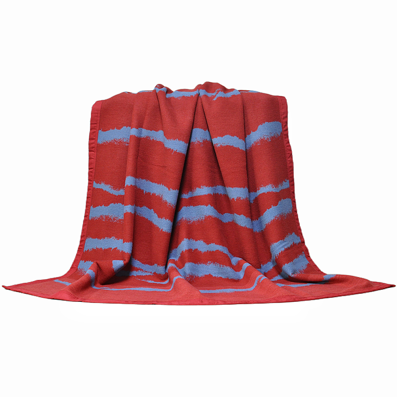Front view of a 100% wool throw blanket with an irregular wave pattern draped over a chair.
