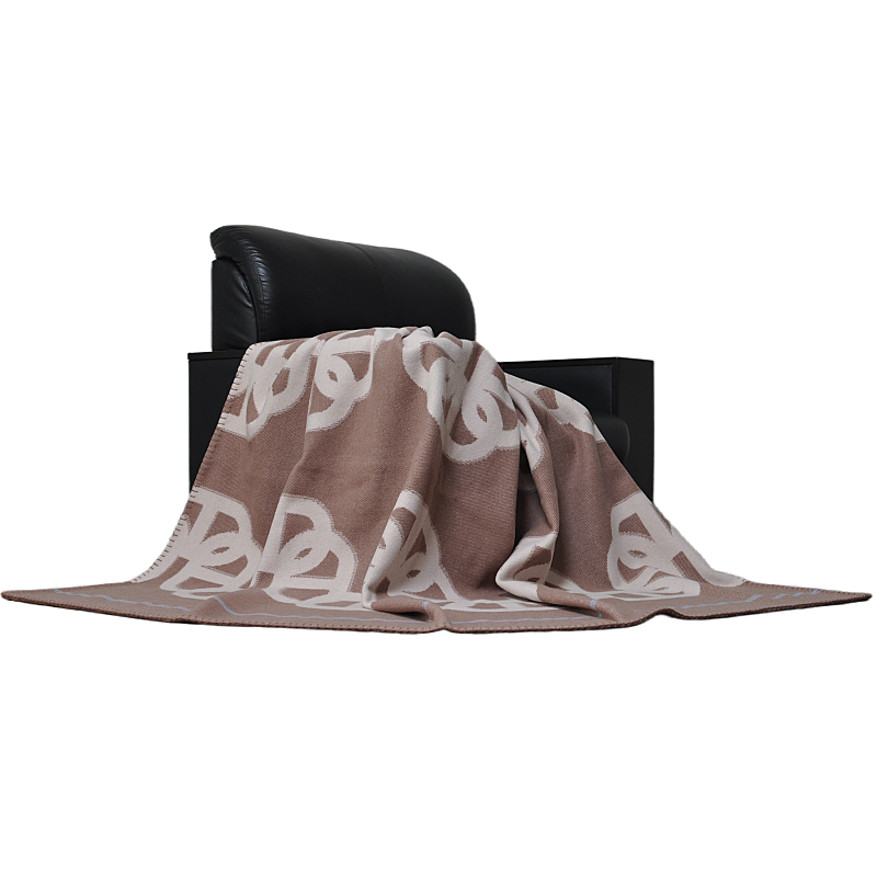 TAK2260 camel-brown lambswool jacquard blanket draped over a black leather chair