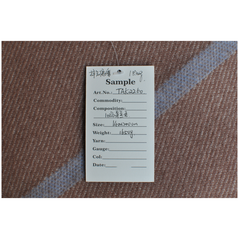 TAK2260 100% lambswool blanket specification label on the camel-brown woven surface